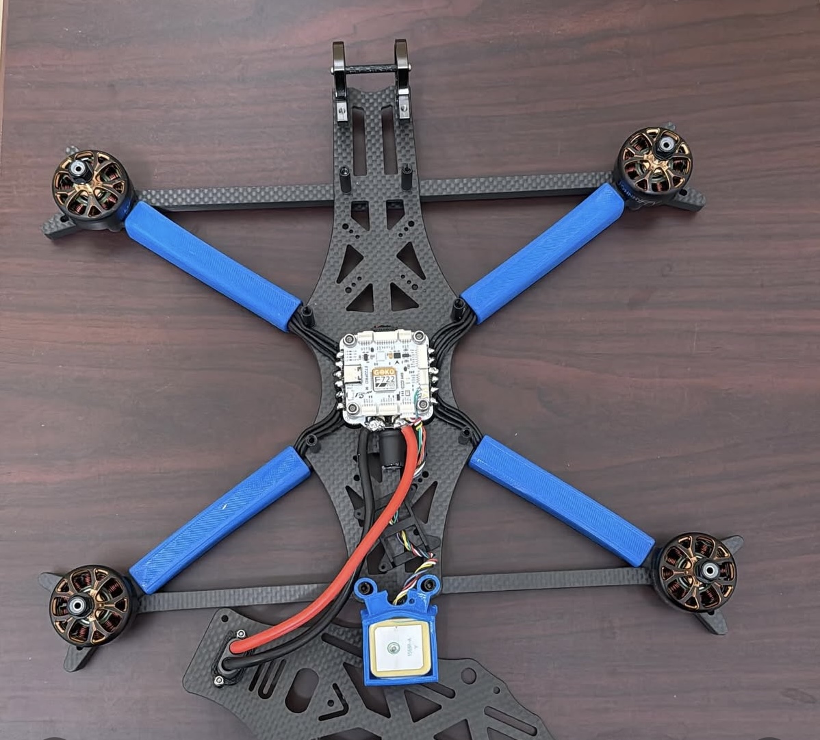 Custom FPV drone build on a carbon fiber frame with blue 3D printed arm guards
